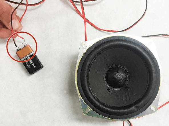 The battery with a greater voltage will aid in amplifying the speaker's sound